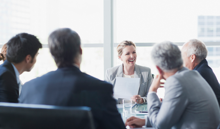 Group of business people sitting round a table in a meeting room Group of business people sitting round a table in a meeting room