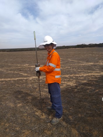 A worker holding a piece of equipment that is used to investigate the soil. 