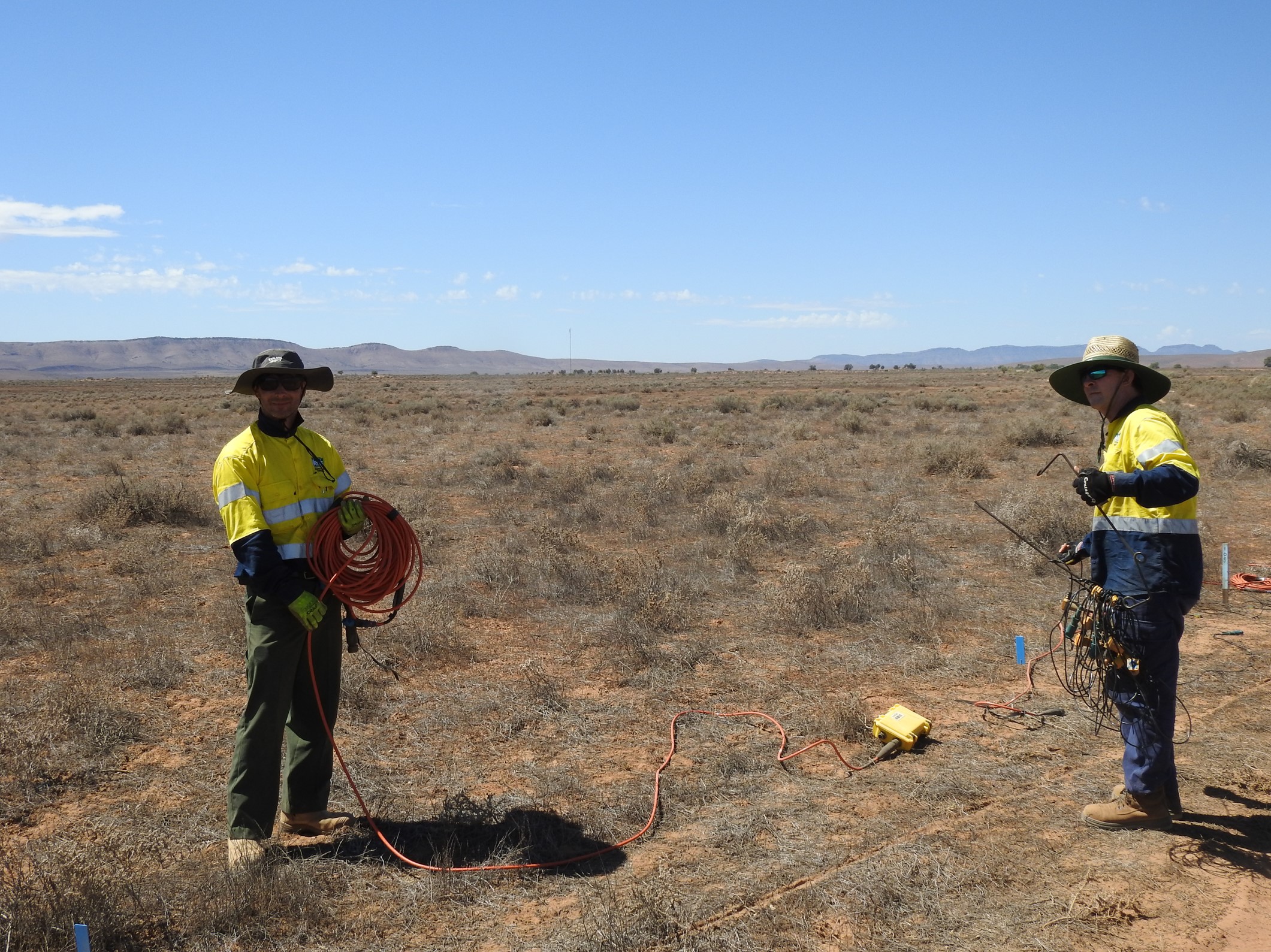 Two workers using equipment to survey the land.