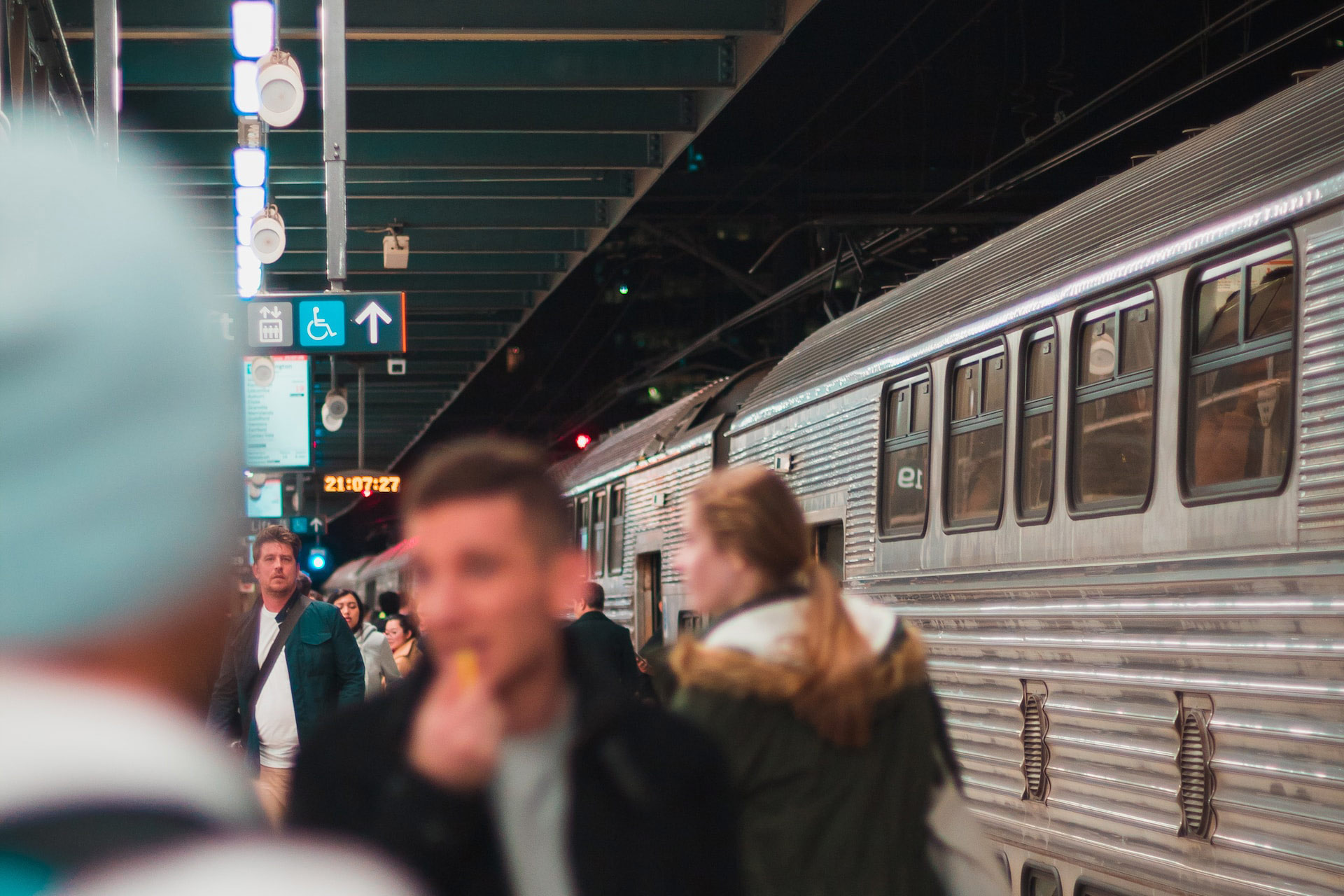 A busy train station platform with people leaving and boarding a train