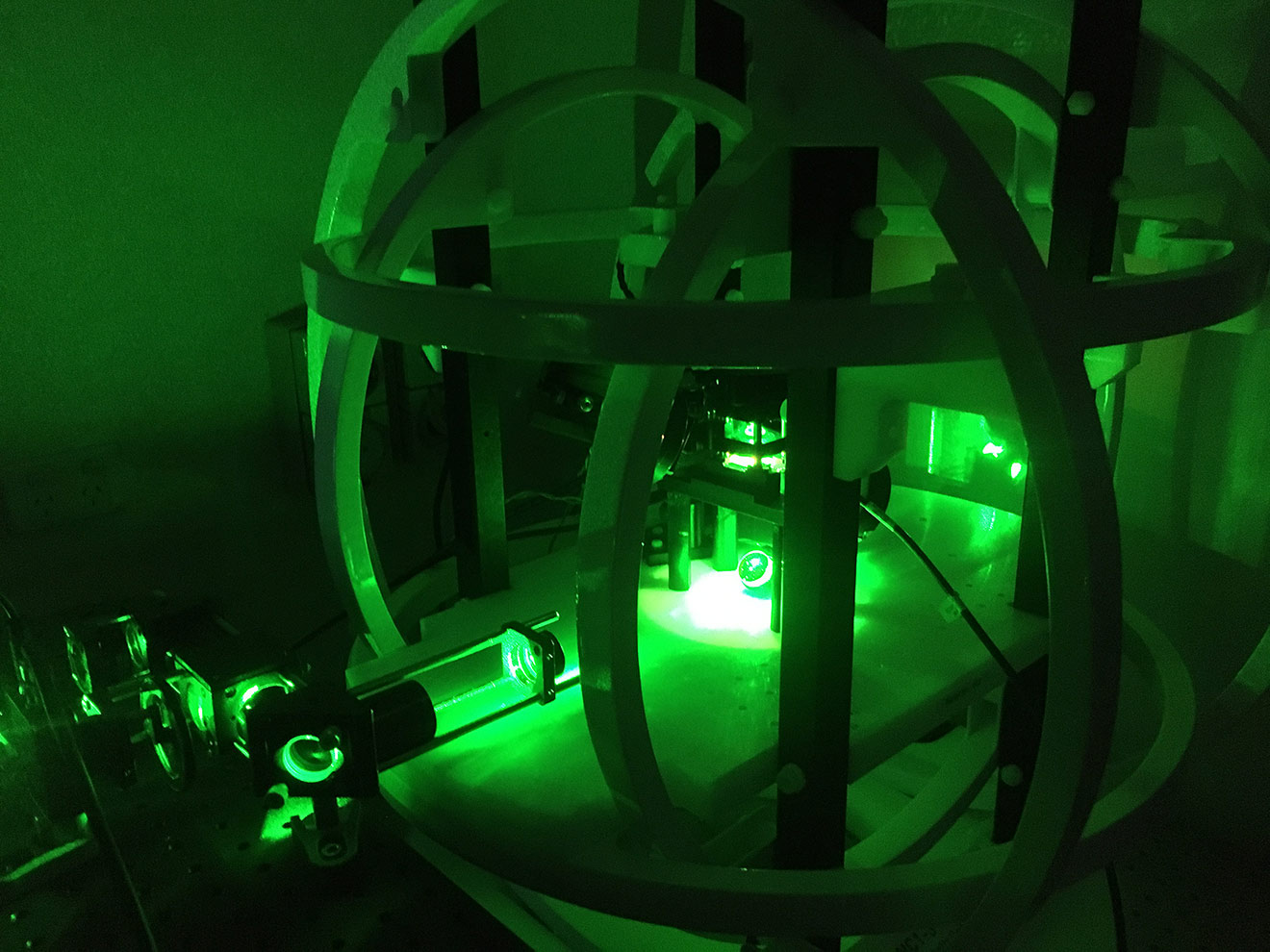 Photo of a device encased in large metal rings and bathed in green light 