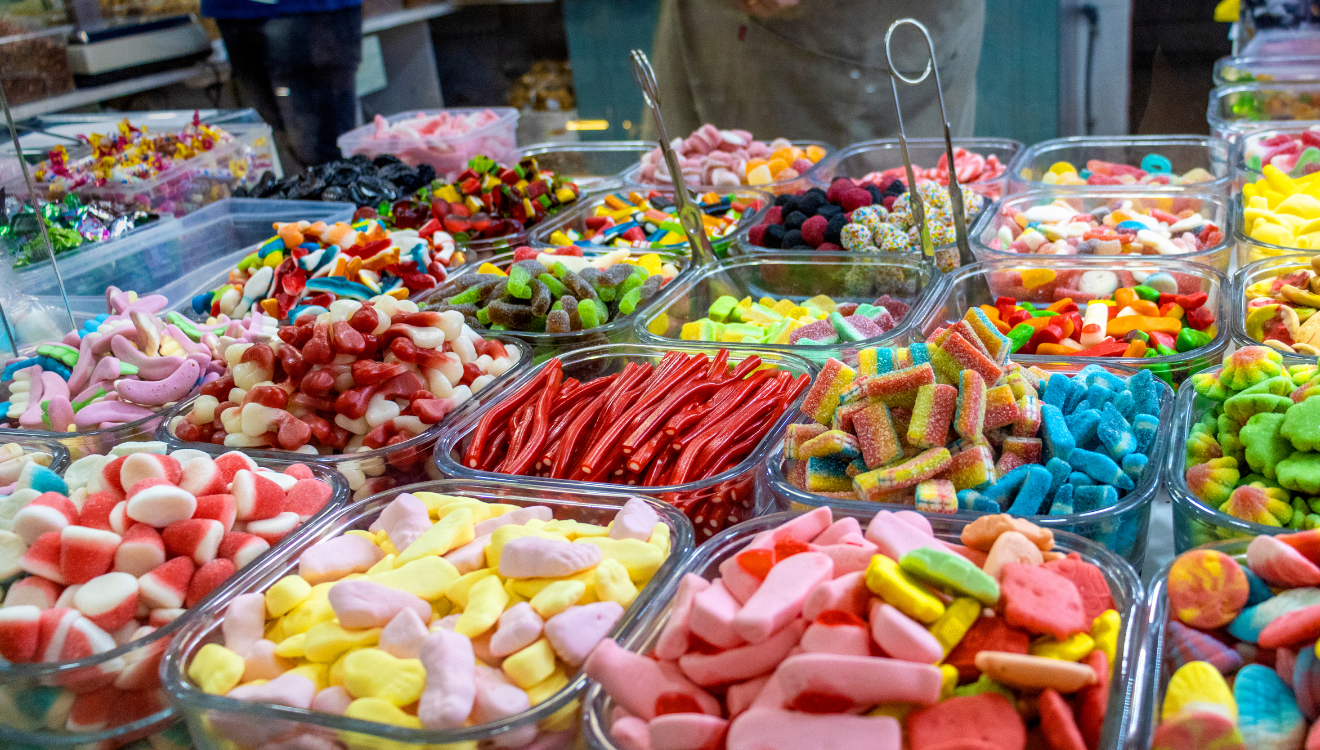 Tubs of colourful lollies in a shop, with tongs provided for self-service selection.
