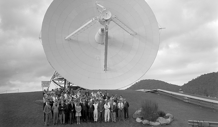 Black and white photo of the Honeysuckle Creek team in front of the telescope. Black and white photo of the Honeysuckle Creek team in front of the telescope.