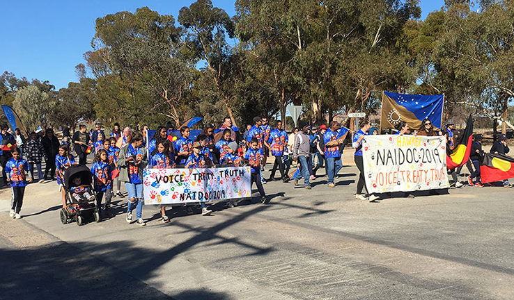 Adults and children carry banners as they march through Hawker during NAIDOC Week. Adults and children carry banners as they march through Hawker during NAIDOC Week.