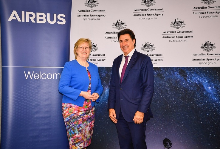Two people standing in front of a banner with the word Airbus on it