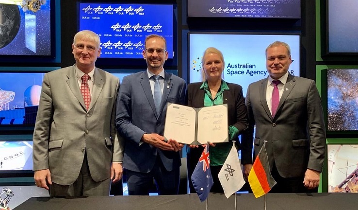 Four people standing together, the centre two holding a document