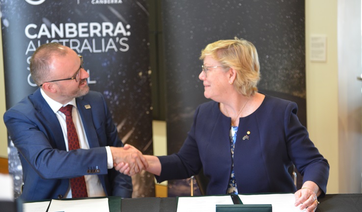 A man and a woman sitting at a table shaking hands