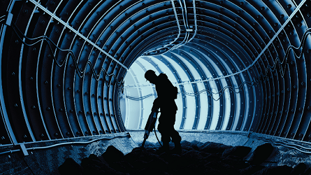 A man using a jackhammer in a tunnel