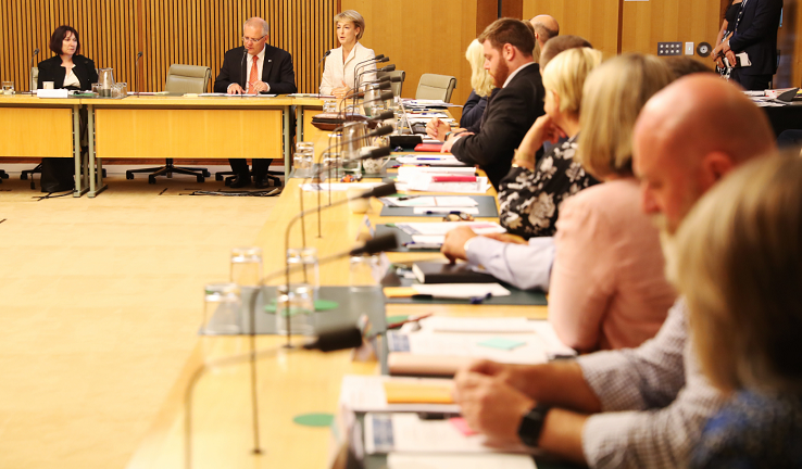 Photo of the roundtable. Tables and chairs occupied by men and women are arranged in an L shape that presumably forms part of a U. The Secretary, Prime Minister, and Minister are at the top of the picture.