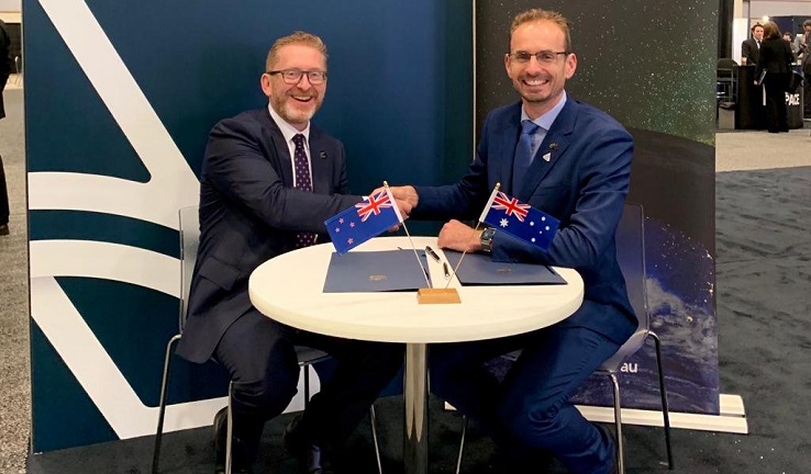 Two men sitting at a table, shaking hands.