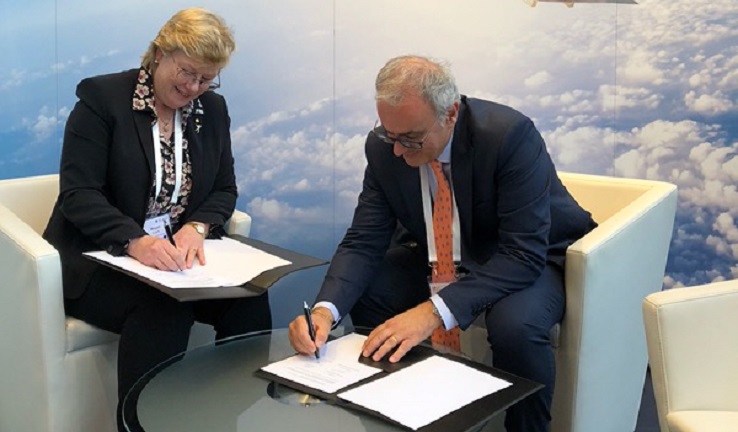 Two people sitting at a table and signing documents