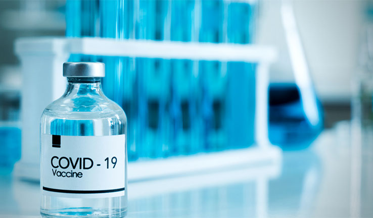 A glass vial with the words COVID-19 Vaccine written on it
