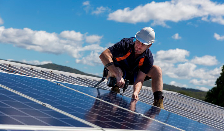 Photo of a man installing solar panels on a roof