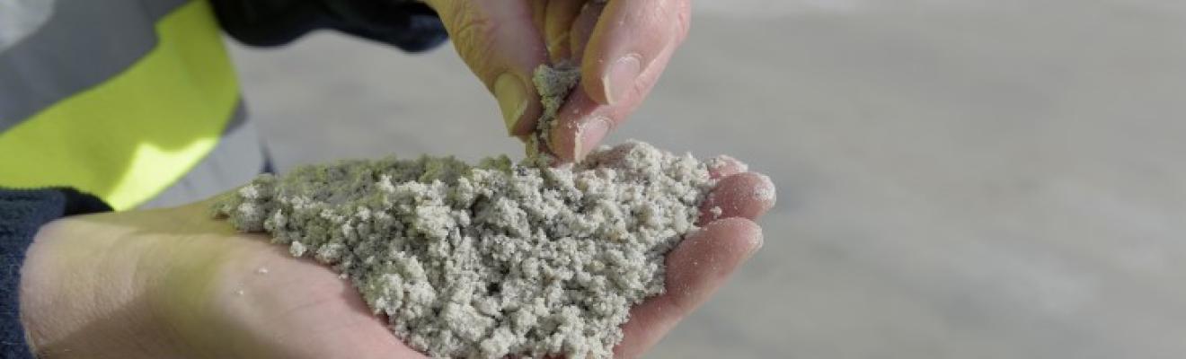 Close up of hands holding a sand-like mineral substance