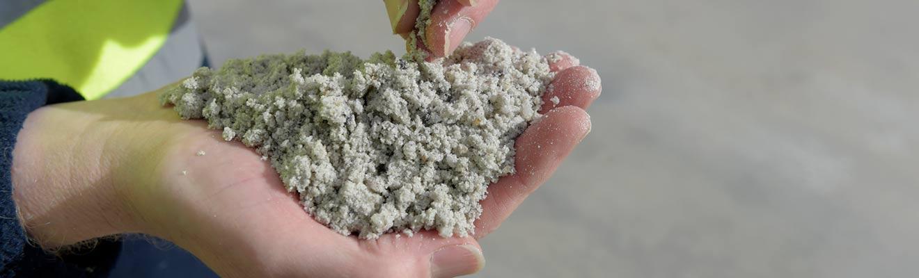 Close up of hands holding a pile of a sand-like mineral