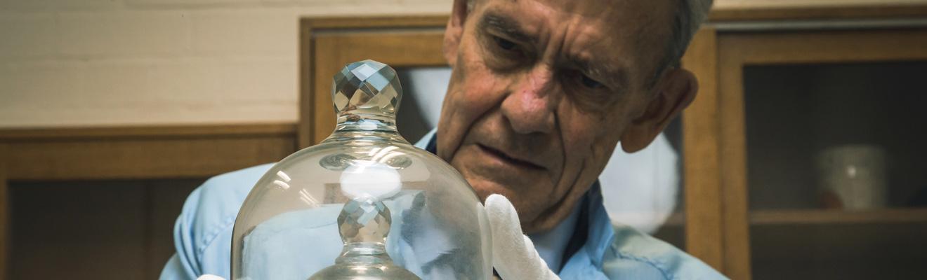 Photo of a man examining a metal weight under glass domes. 