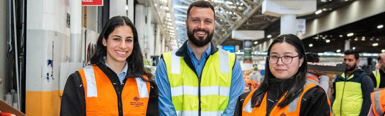 Three trade measurement inspectors standing in a fruit and vegetable market