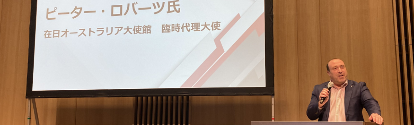Man stands at lectern with microphone and screen behind