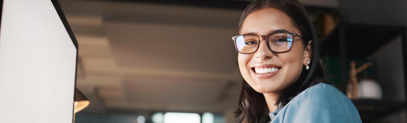 Young woman sitting at a computer smiling