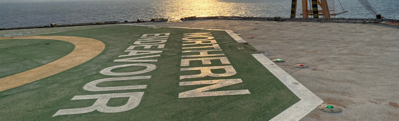 Photo of a platform on the Northern Endeavour with the logo and ocean in the background. 