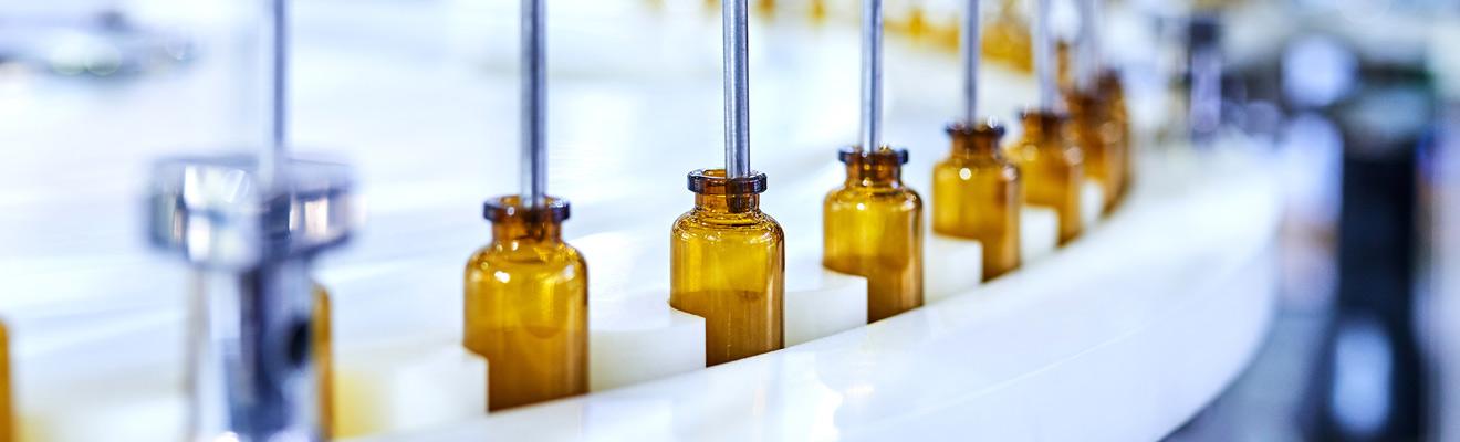 Small glass vials being filled in a manufacturing facility