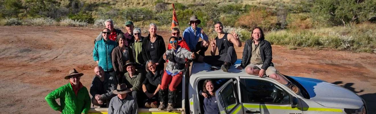A team of people on a dual-cab ute in the Australian Outback.