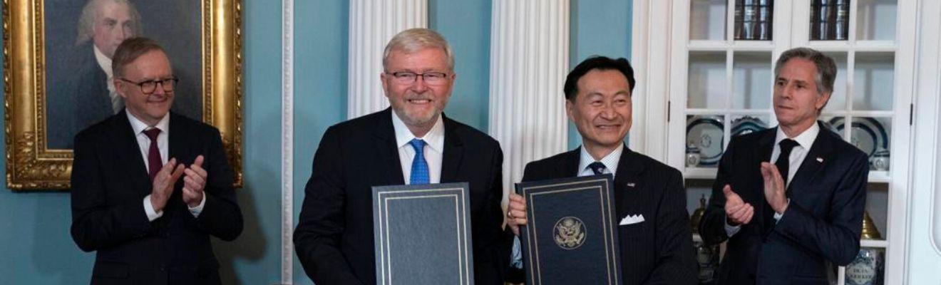 Photo of Australia's Ambassador to the US, Kevin Rudd, and State Department official CS Eliot Kang holding the signed agreements. The Prime Minister, Anthony Albanese, and US Secretary of State Antony Blinken are standing on either side and applauding.