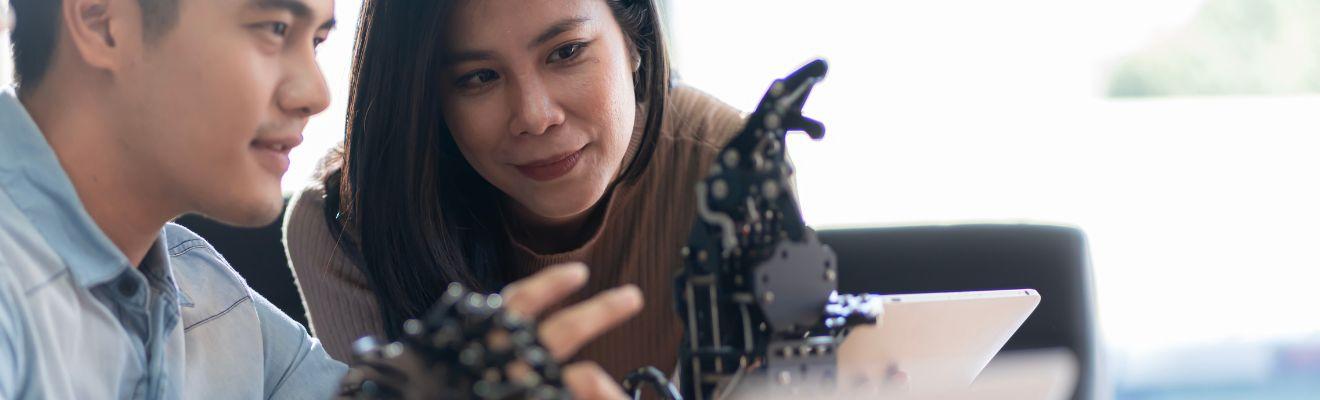 Man and woman looking at a robotic hand.
