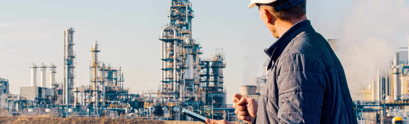 Worker wearing a hard hat while holding a device looks at gas infrastructure