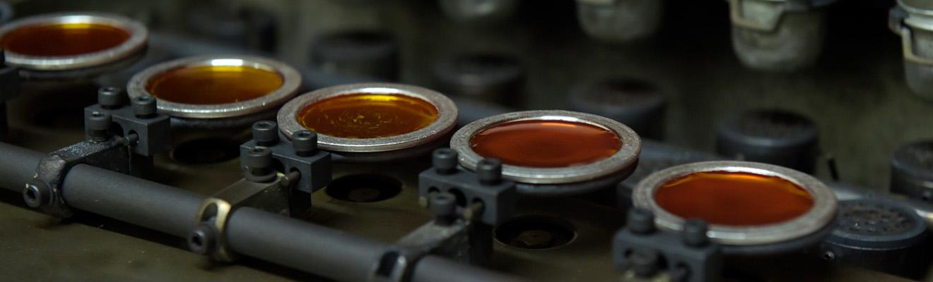 A series of shallow metal containers containing brown glass discs