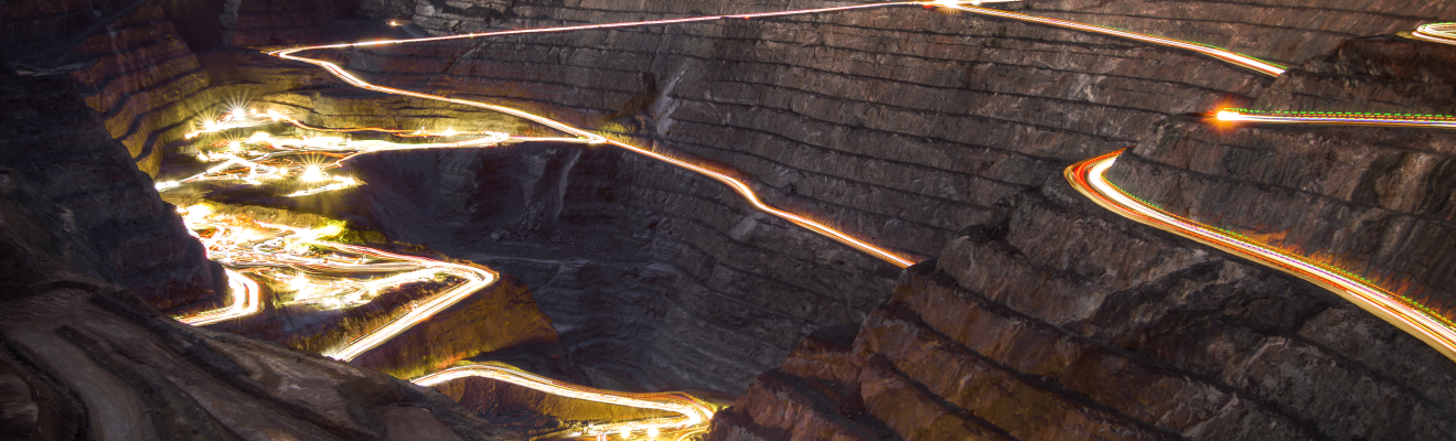 An open-cut mine site, with light trails caused by vehicles. The whole image is tinted blue 
