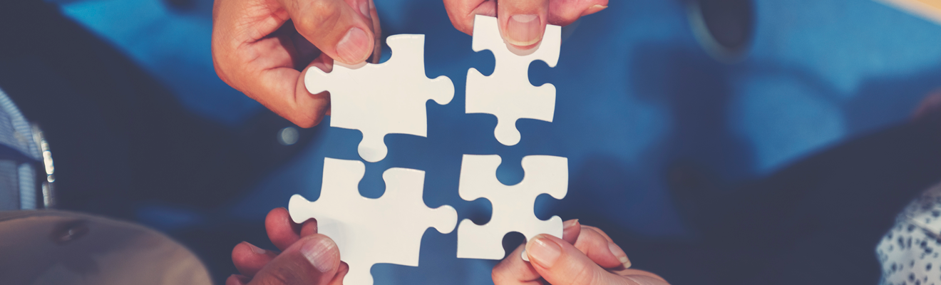 Diverse group of people all with a part of a jigsaw puzzle symbolising team work and solving challenges. 