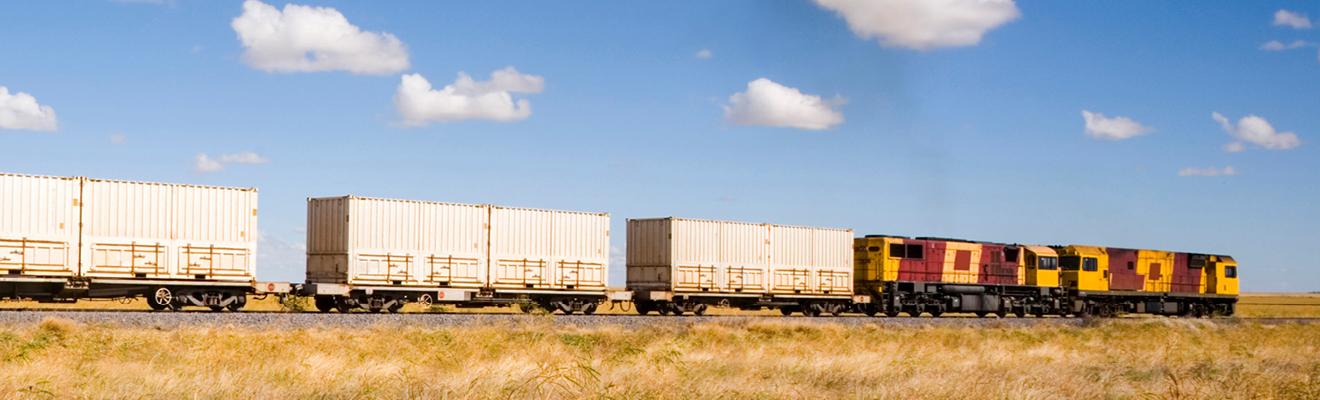 Train carrying shipping containers in country area 