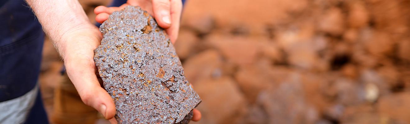 Closeup photo of a pair of hands holding iron ore.