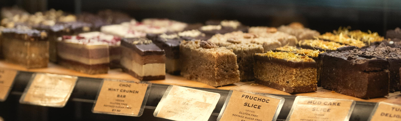 A selection of cakes and patisseries items for sale behind a glass counter