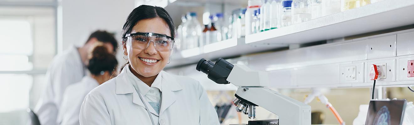 Female scientist dressed in a lab coat. In a modern laboratory with microscope.