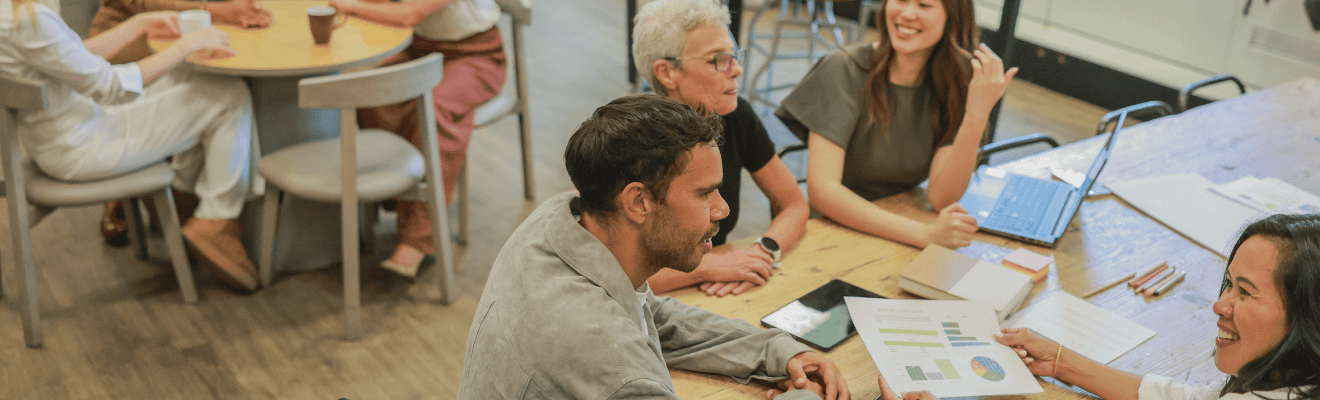Group of people from diverse backgrounds talking while seated at a table. 