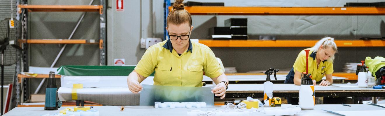 Photo of a woman working with moulded plastic and signage in an industrial warehouse