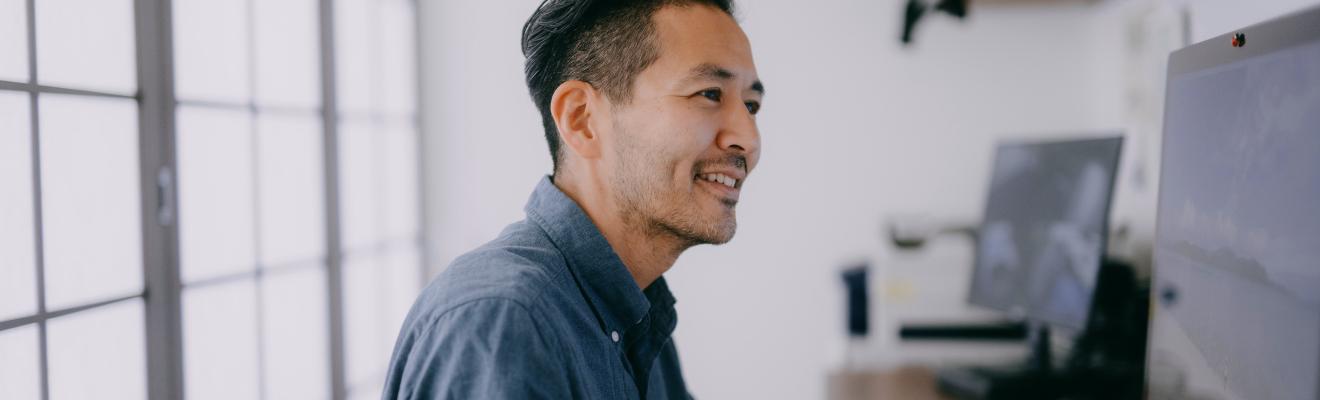 Close up photo of an office worker sitting at their desk and working at a computer