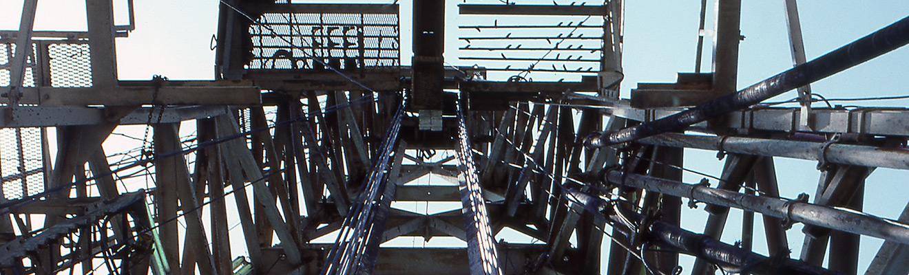 Photo of offshore petroleum infrastructure, looking upward through scaffolding toward the sky.