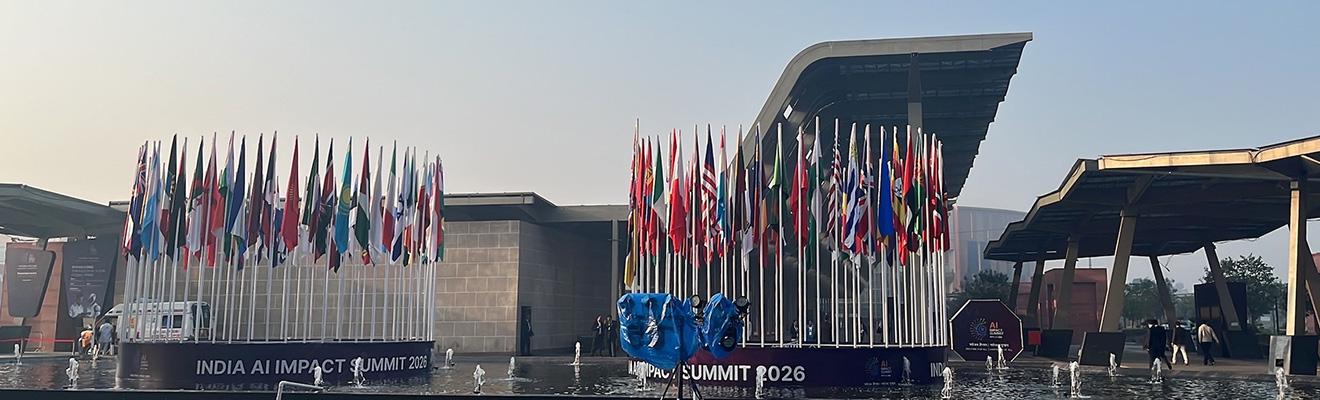 Entrance plaza of Bharat Mandapam, Pragati Maidan, during the India AI Impact Summit 2026, with international flags displayed outside the venue.