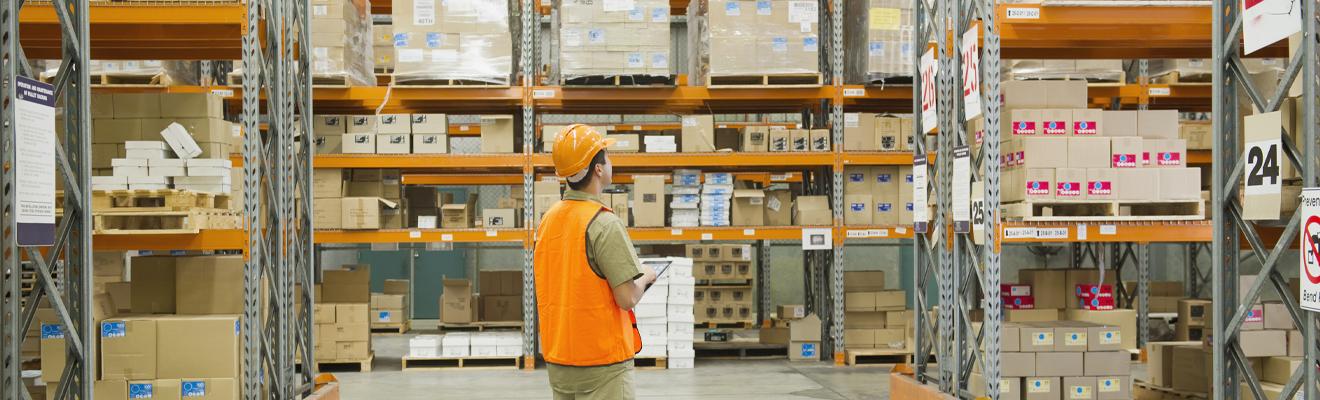 Worker in high-vis vest taking stock of supplies in a warehouse