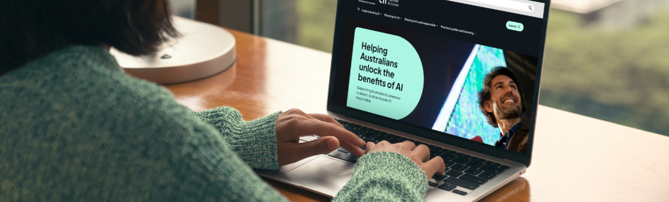 Person typing on a laptop with the screen showing the home page of the Ai.gov.au website