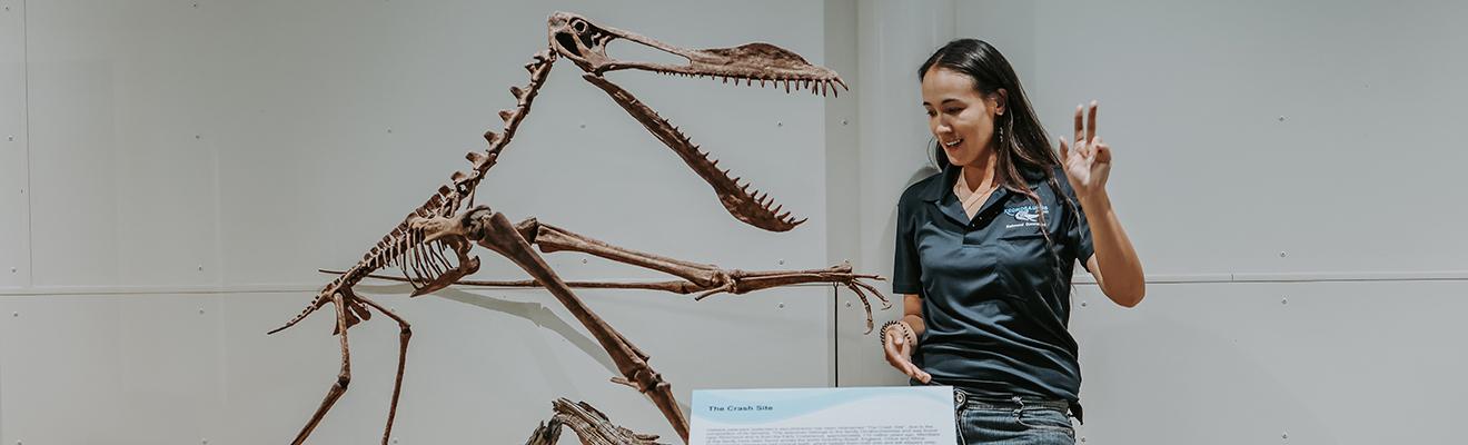 Woman palaeontologist explaining a dinosaur skeleton in an exhibition