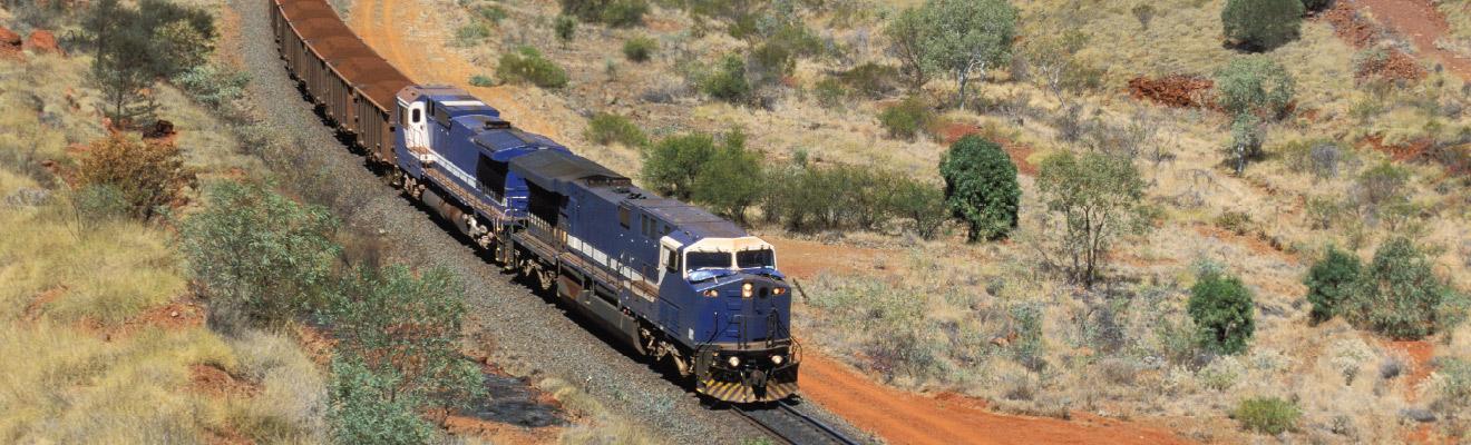 One of the world's longest and heaviest trains carries a load of Pilbara iron ore to port through a rugged desert landscape in outback Western Australia.