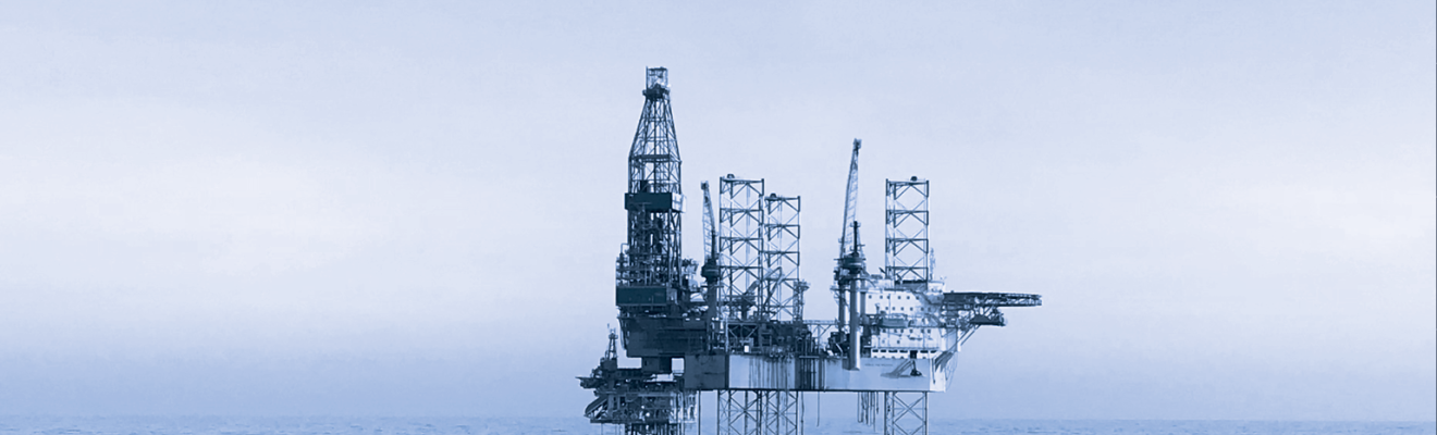 Image of an oil rig in the middle of the ocean. The image has a blue tint.