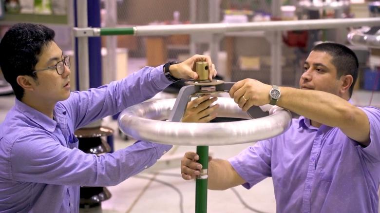 Screen shot from the video showing two people working on electricity equipment