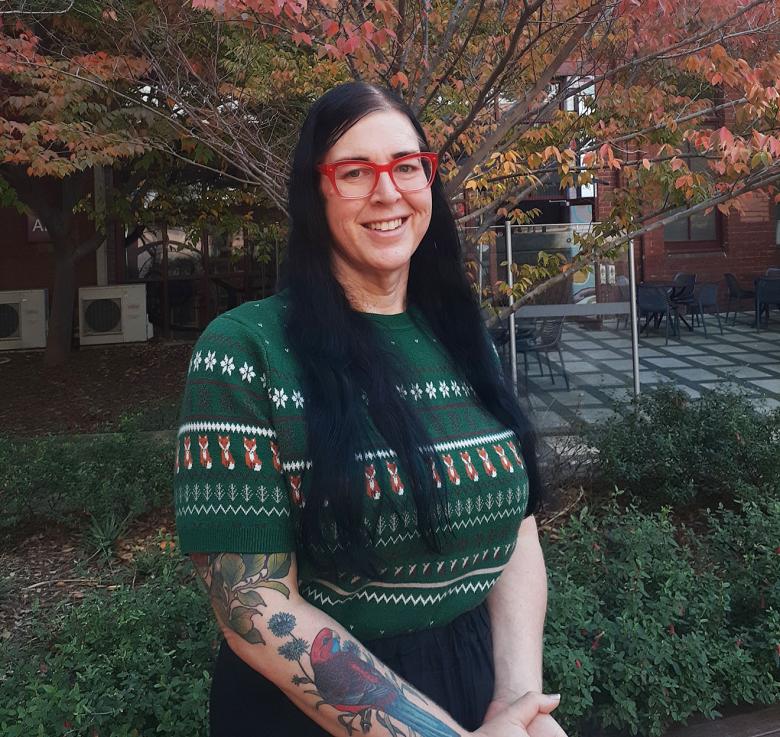 Photo of Deanne Fisher standing in front of an autumn tree on a university campus