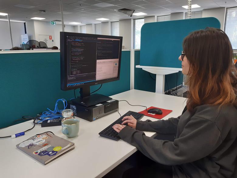 Kiowa Scott-Hurley sitting at a desk coding on a desktop computer