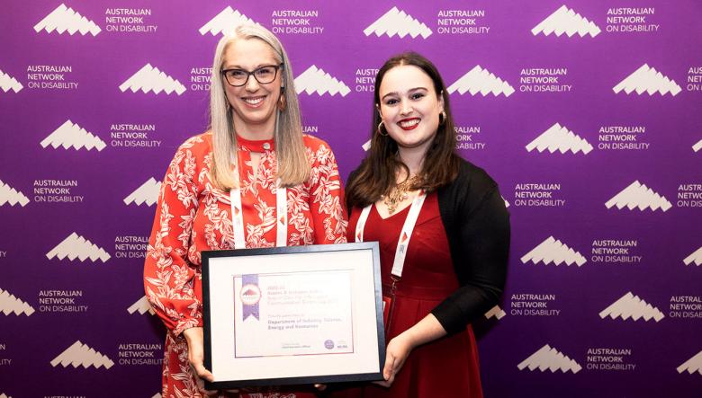 Two women displaying an award at an awards ceremony